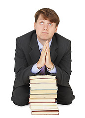 Image showing Student prays before examination on pile of textbooks