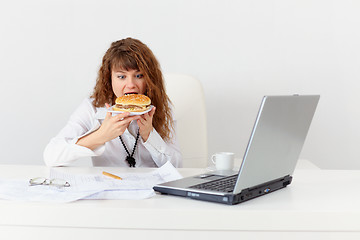 Image showing Young girl has hastily dinner sandwich at office