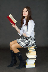 Image showing Girl - student sitting on pile of textbooks