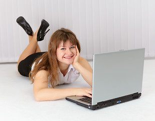 Image showing Happy young woman lying on floor with laptop