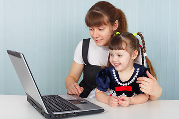 Image showing Mother and daughter sitting at table with laptop