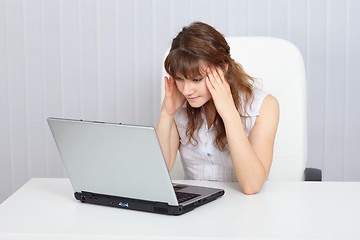 Image showing Young tired woman working with laptop at table