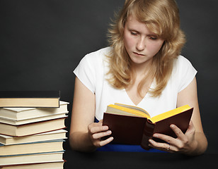 Image showing Young woman reads book against dark background
