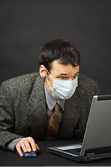 Image showing Surprised businessman in medical mask works in Internet