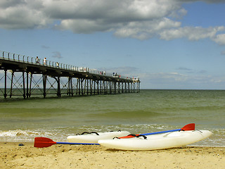 Image showing Two canoes on the shore with a pier in the background