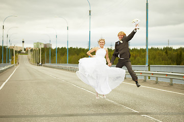 Image showing Newly married pair jumps on highway