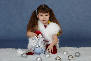Image showing Child sits on blue with Christmas tree ball