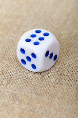 Image showing One dice on brown canvas