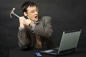 Image showing Furious young man breaks hammer computer