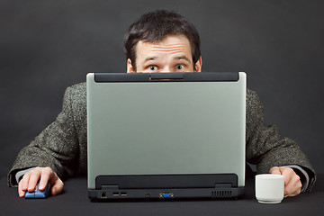 Image showing Frightened people hiding behind computer screen