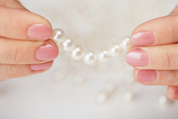 Image showing Female fingers hold thread with pearls