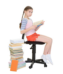 Image showing Schoolgirl learns lessons near big pile of textbooks