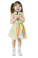 Image showing Little girl looks at you through large magnifying glass