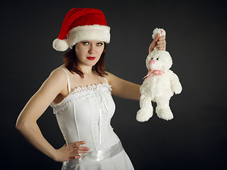 Image showing Young woman in Christmas cap holds a rabbit