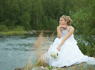 Image showing Sad bride sits on river bank