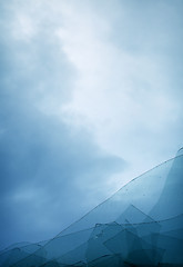 Image showing Cloudy blue sky through broken window