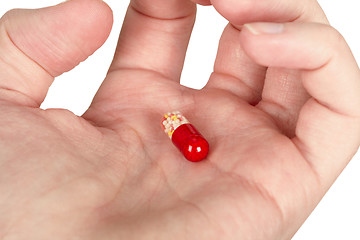 Image showing Mysterious multi-colored pill in palm