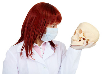 Image showing Woman in medical uniform looks at human skull