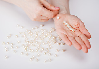 Image showing Female hands collecting beads from pearls