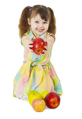 Image showing Happily smiling little girl gives an apple