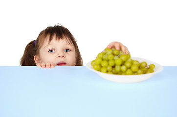 Image showing Child reaches for grapes lying on table