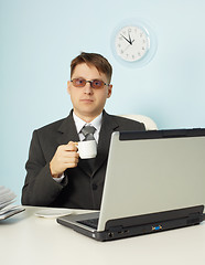 Image showing Serious man at office with laptop and cup of coffee