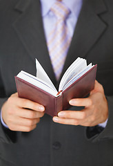 Image showing Businessman checks schedule of day in organizer