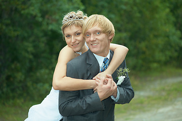 Image showing Smiling happy bride embraces groom