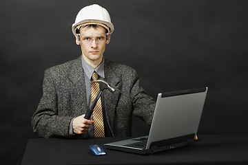 Image showing Man in helmet with hammer repairs computer