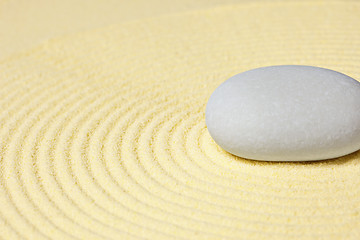 Image showing Round stone lying on sand with circular pattern