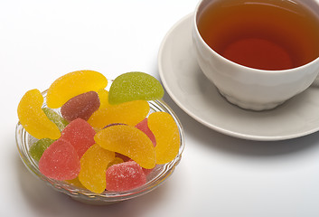 Image showing Cup of tea and fruit candy.