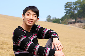 Image showing handsome forties man is sitting on the grass relaxing and smilin