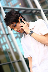 Image showing young businessman in a suit holding mobile phone in front of mod