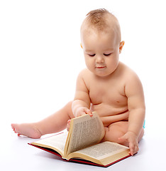 Image showing Little child play with book and magnifier