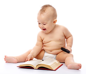 Image showing Little child play with book and magnifier