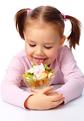 Image showing Little girl licks fruit salad