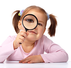 Image showing Curious girl is looking through magnifying glass