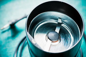 Image showing Empty electrical coffee-mill machine on the green tabletop (without top cover)