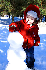 Image showing kid on the yard is making a snowman