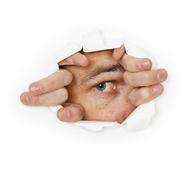 Image showing Man looks through a hole in paper