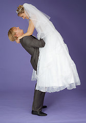 Image showing Strong groom holds admired bride on hands