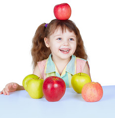 Image showing Happy girl playing with apples sitting at table