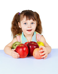 Image showing Little girl playing with apples sitting at table