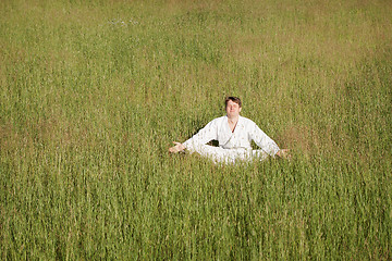 Image showing Man in kimono meditates sitting in grass