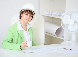 Image showing Woman - a builder in helmet with cup in hand