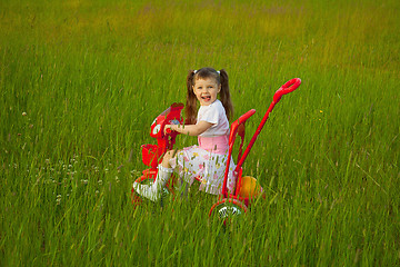 Image showing Little girl rides a bicycle on field