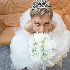 Image showing Amusing bride sits on sofa with bouquet - top view