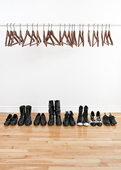 Image showing Row of shoes and empty hangers