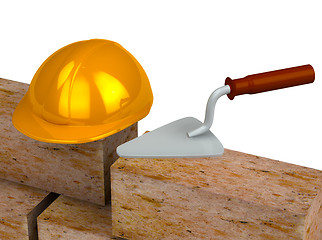 Image showing Trowel, bricks, yellow plastic helmet