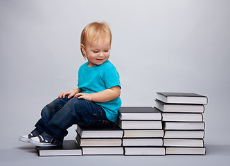 Image showing Kid sitting on a a steps made of books